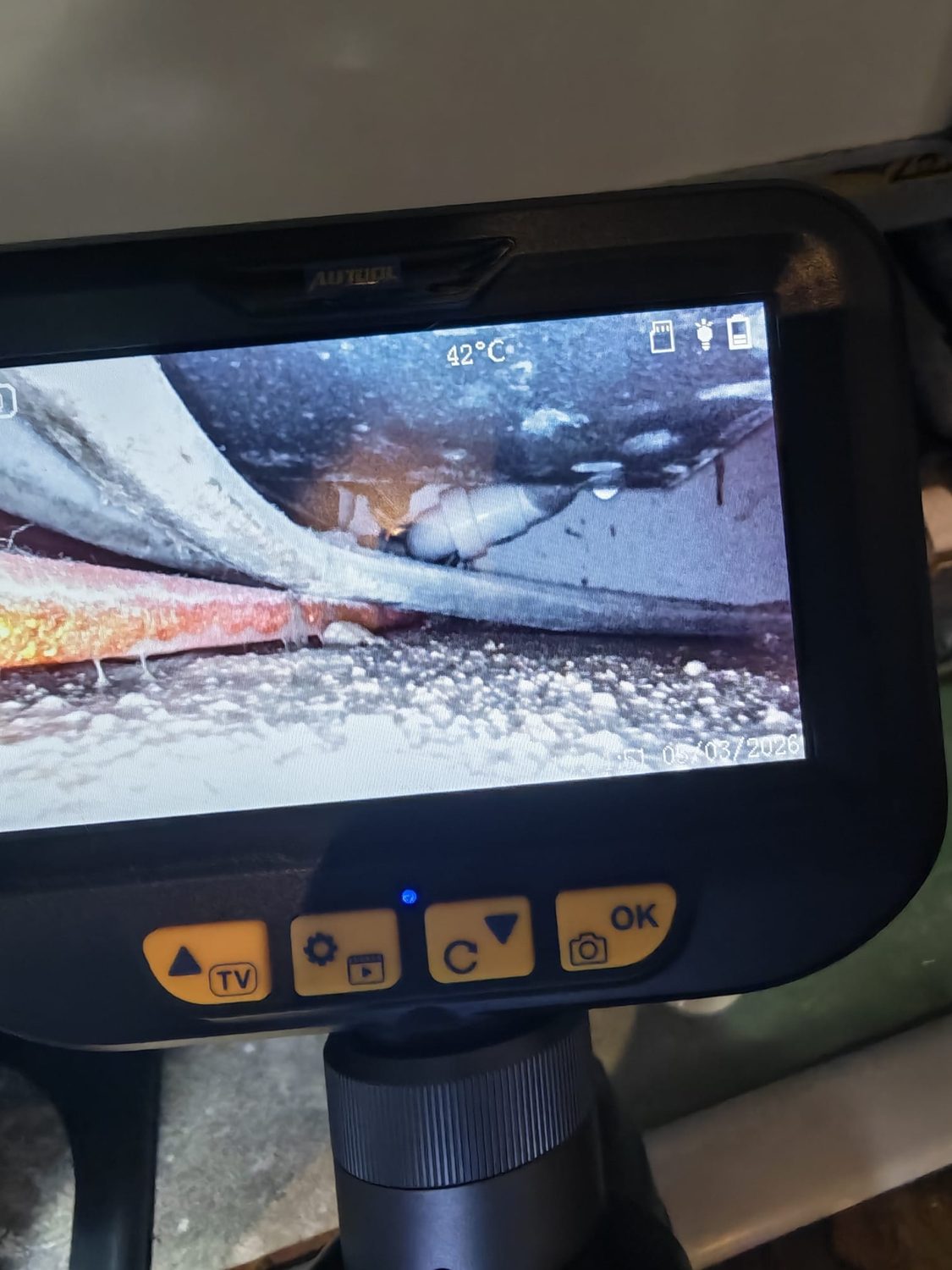 Inspection camera screen showing insulated pipework under a floor void, reading 42 degrees Celsius